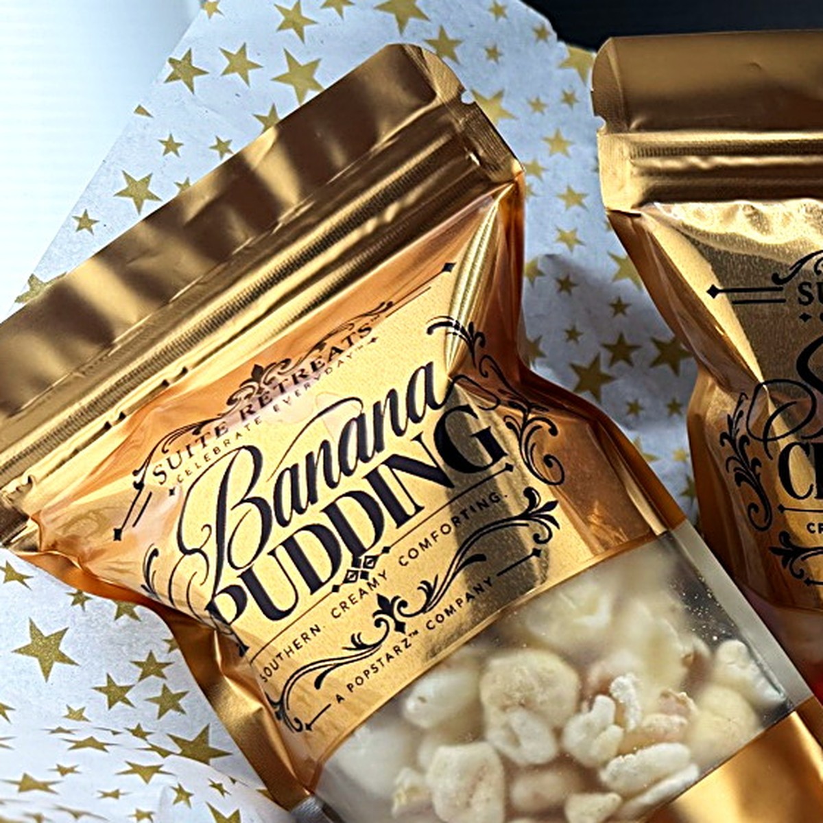 A gold Suite Retreats Banana Pudding pouch on gold-star tissue, label front and centre