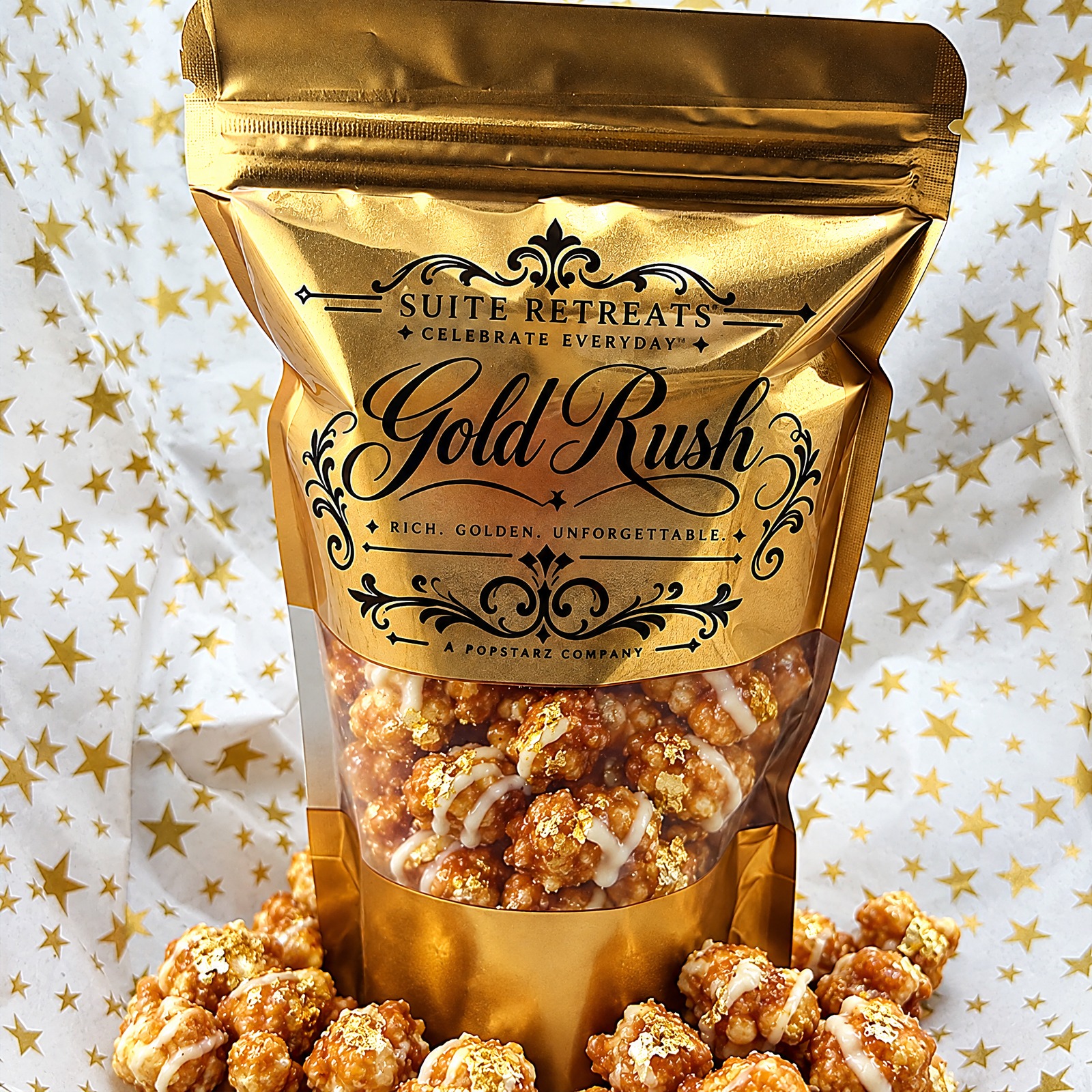A gold Suite Retreats Gold Rush pouch of caramel and white chocolate popcorn with edible gold, on gold-star tissue