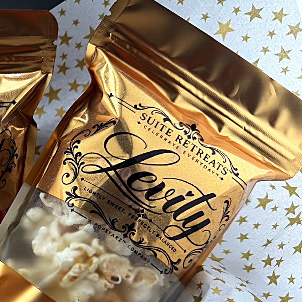 A gold Suite Retreats Levity kettle corn pouch on gold-star tissue, label front and centre